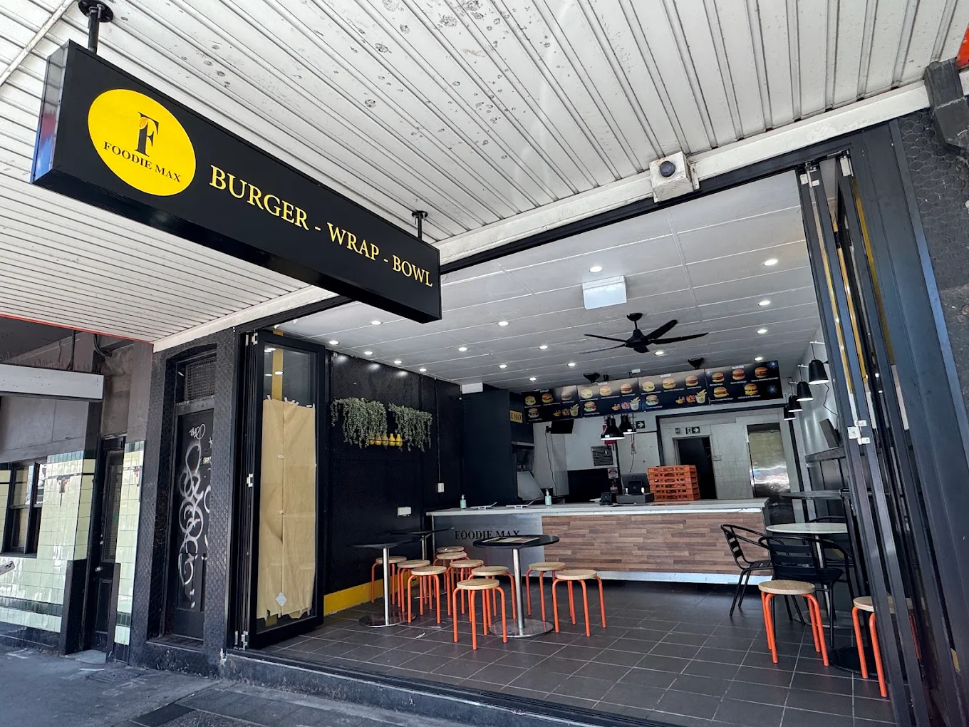 Foodie Max shopfront with the Burger, Wrap, 
  Bowl sign and an open dining room